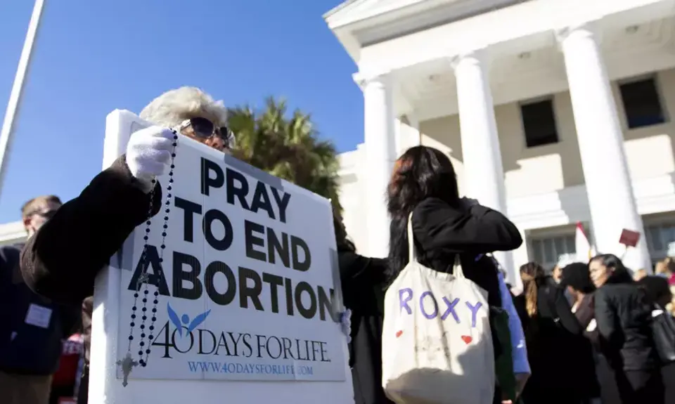 Protestors hold a sign that reads "Pray to end abortion"