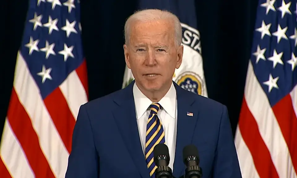 President Biden giving a speech in front of a pair of American flags