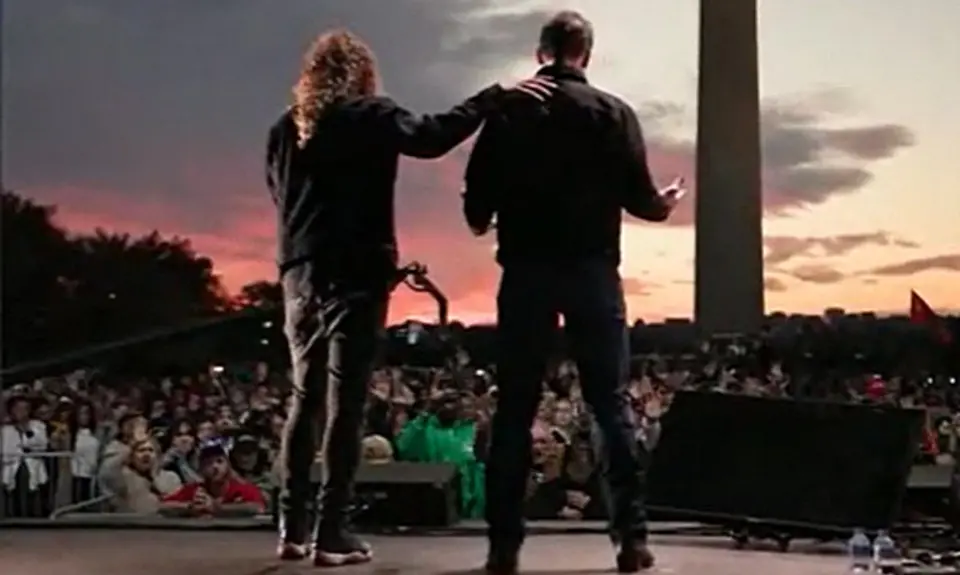 Photo from behind Sean Feucht and Josh Hawley with crowd in front of them and Washington monument behind the crowd. 