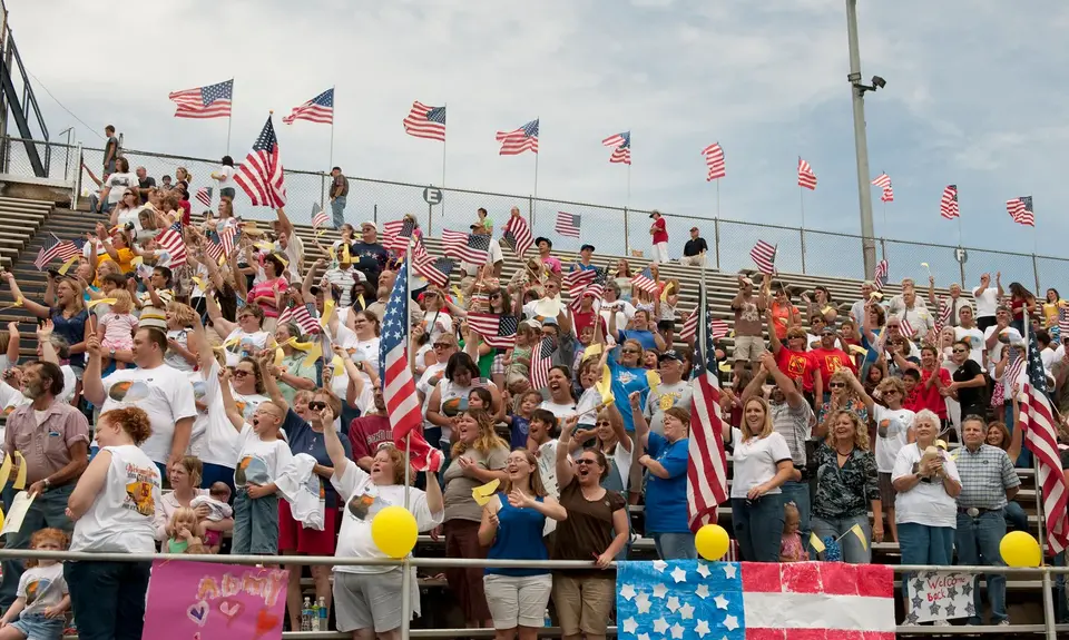 Rallygoers wave the American flag from bleachers