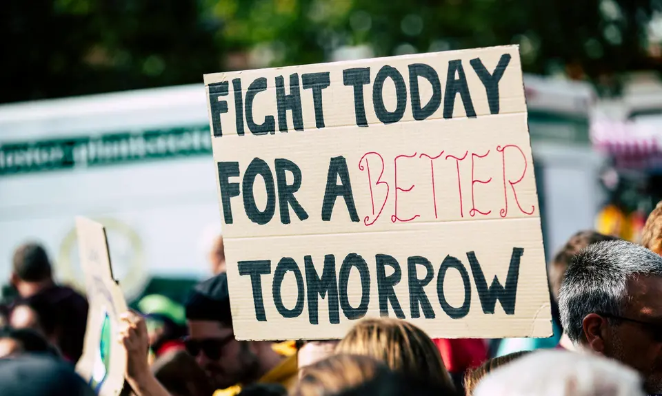 Protesters holding a sign that reads "fight today for a better tomorrow"