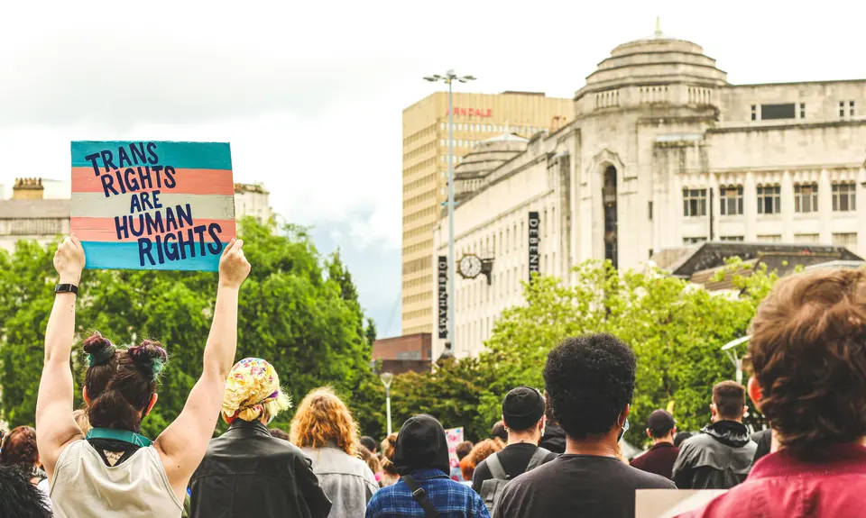 protestors holding a sign that reads "trans rights are human rights"