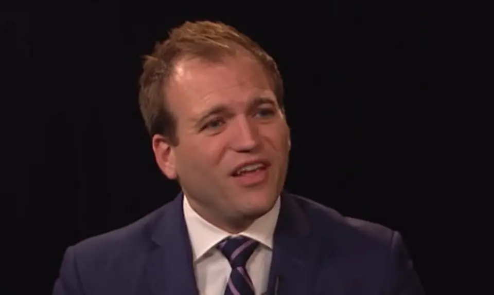 Image taken from video: Johnnie Moore in suit and tie against dark background, speaking to off-camera CBN hosts.