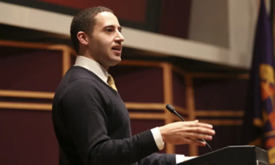 Photo of Svante Myrick wearing a black sweater and speaking in front of a podium.