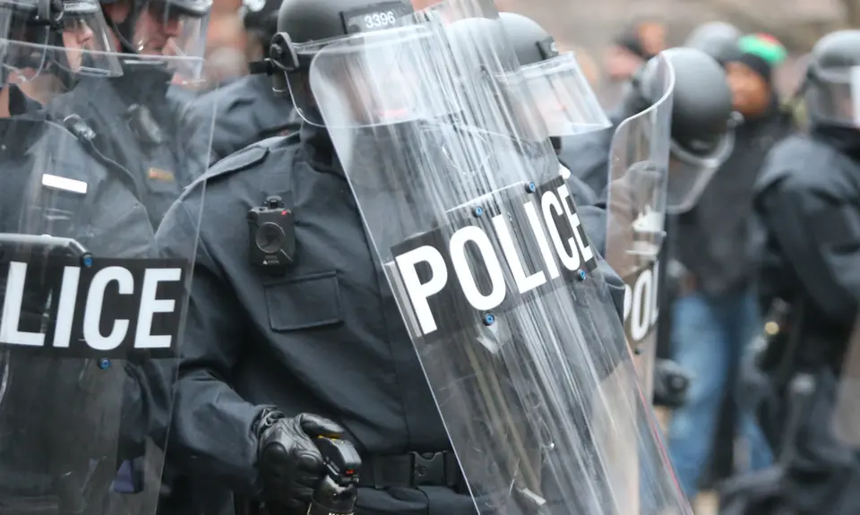 A group of police in riot gear with riot shields.