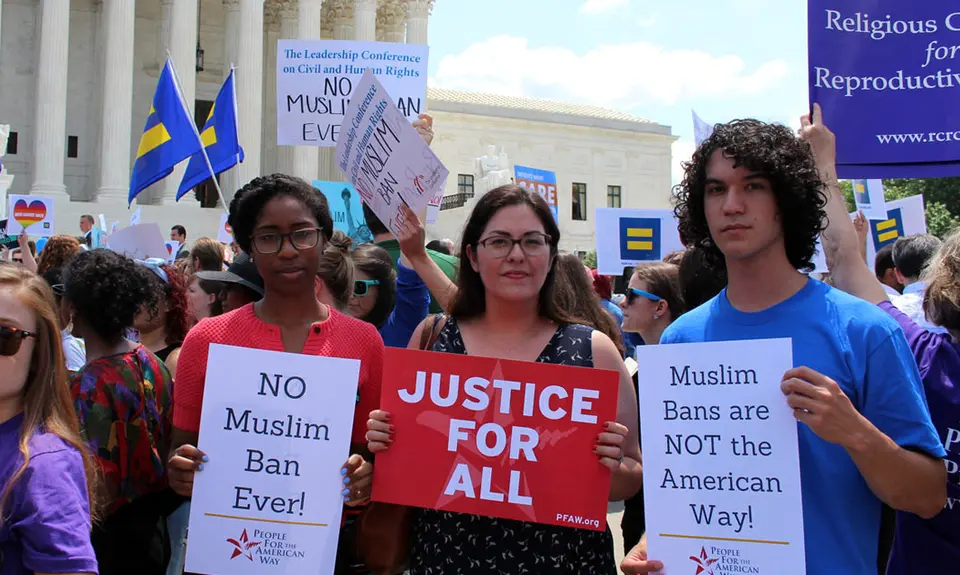 three people holding pfaw signs at a rally in front of supreme court