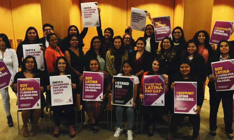 A group of people holding signs that say "Close the Latina pay gap" "I support Latina workers" and "Soy latina"