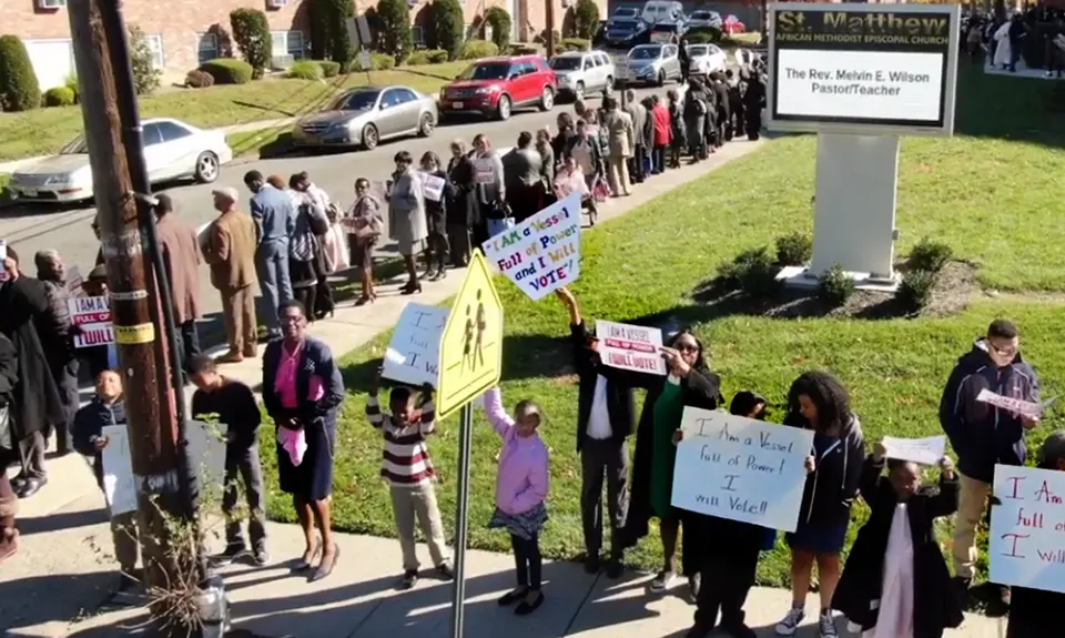 A group of people outside a church holding signs