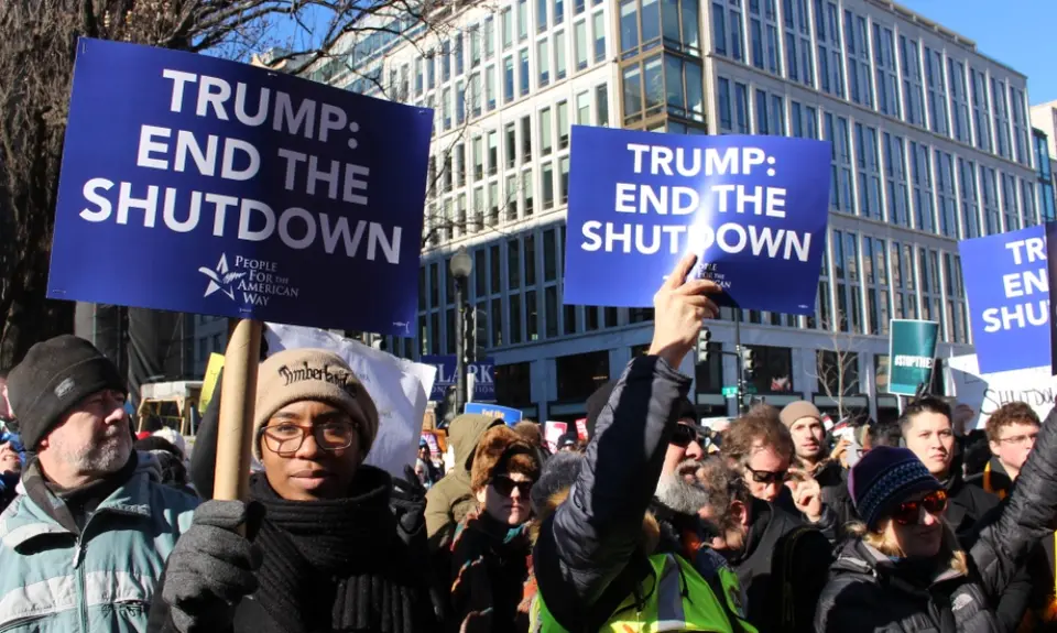 A group of people holding signs that say "Trump: End the shutdown"