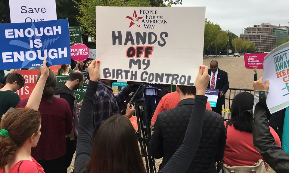 People hold signs that say "Enough is enough," "Hands off my birth control" and "Don't take away our health care ever"