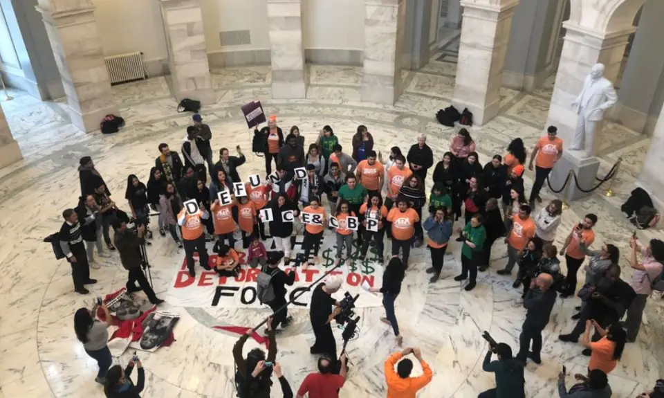 A group of protesters hold signs that say "Defund ICE and CBP"