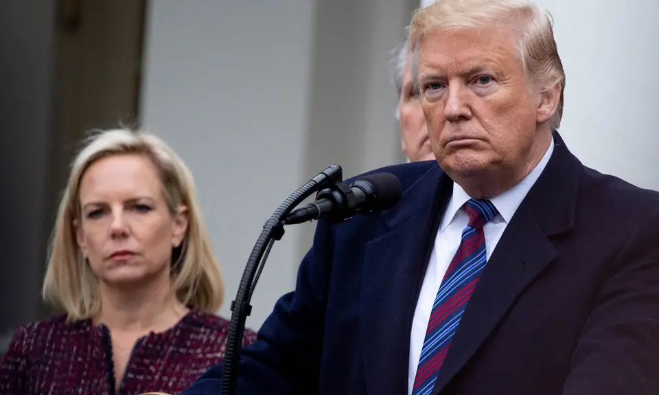 Donald Trump stands at a podium with Kirstjen Nielson