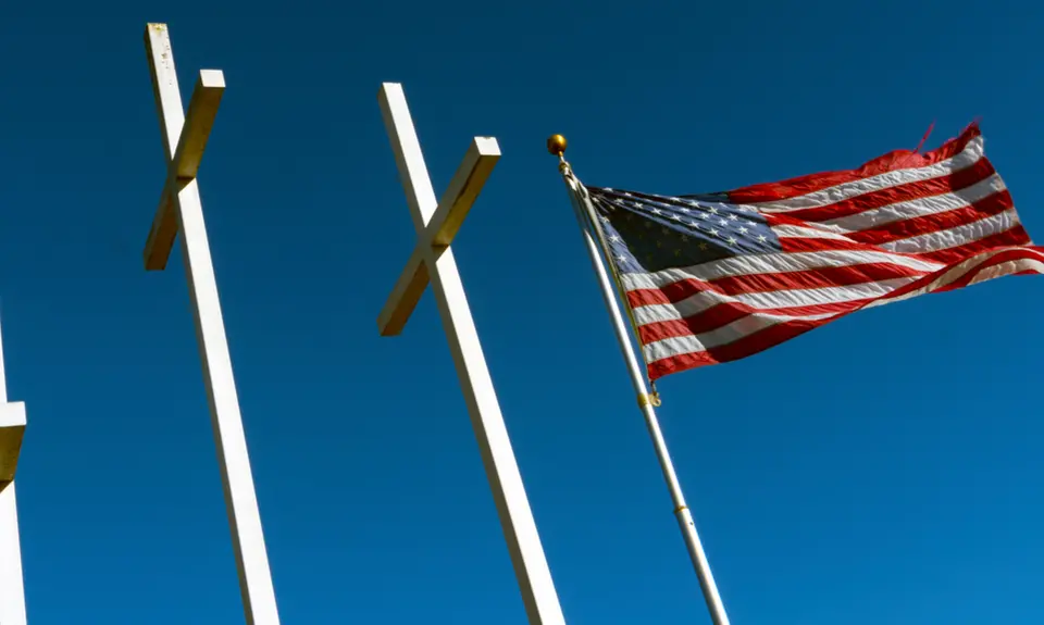 The American flag waves next to three large crosses