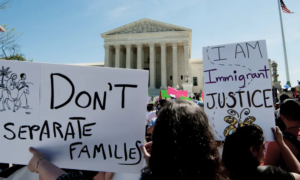 Rally-goers in front of the Supreme Court holding signs that say "Don't separate families" and "I am immigrant justice"