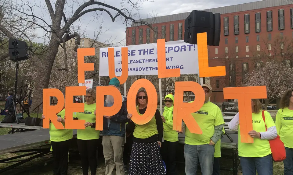 A group of people in neon yellow shirts holding letters that spell 'FULL REPORT"