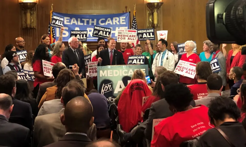 A group of people hold pro-Medicare signs in the senate.