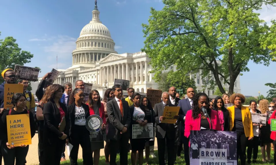 Activists stand outside the U.S. Capitol Building and hold signs that support Brown v. Board