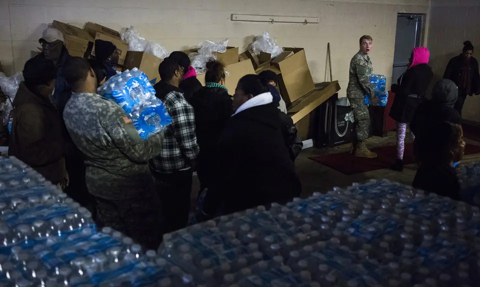 Members of the Michigan National Guard distribute bottled water to residents.