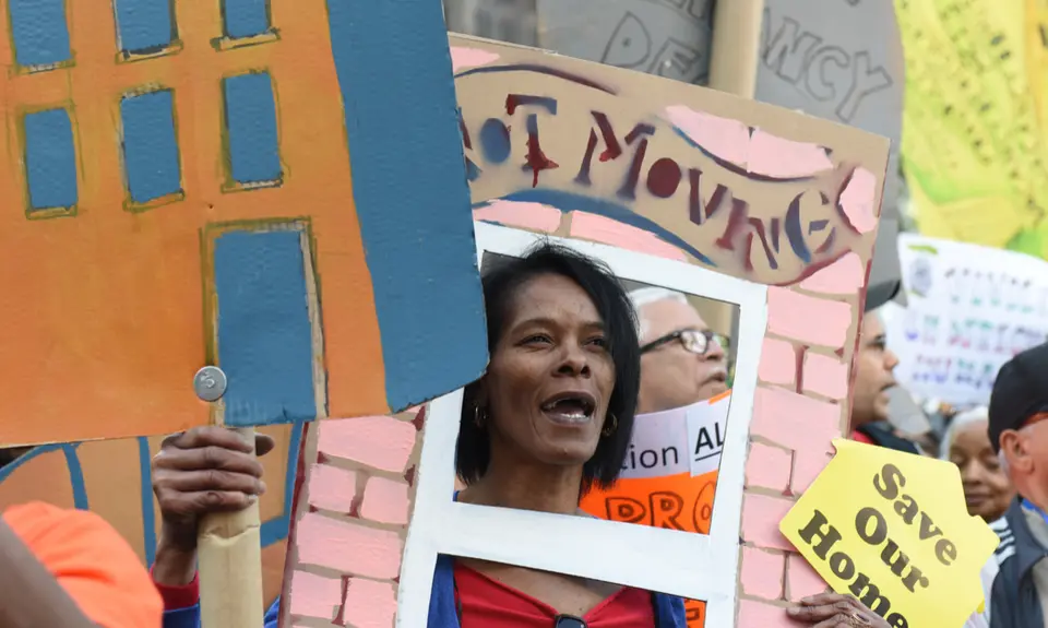 Activists march across the Brooklyn Bridge holding signs demanding affordable housing.