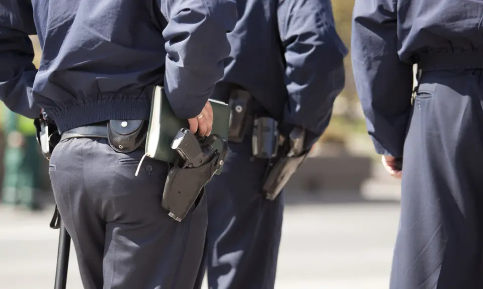 A close-up of police officers waists with guns on their hips