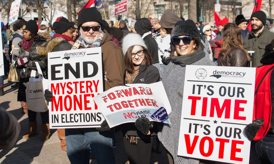 Protesters hold signs and participate in the 10th Annual Moral March