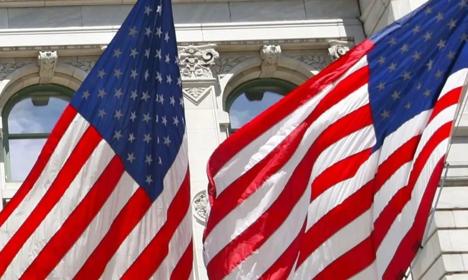 picture of two American flags against a white building