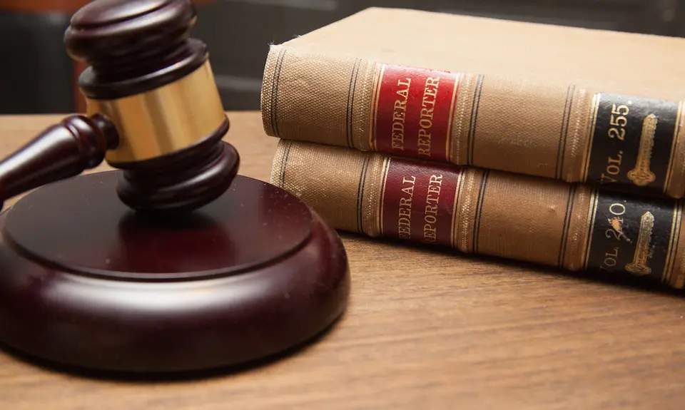 Judge's gavel in a courtroom, stack of law books.