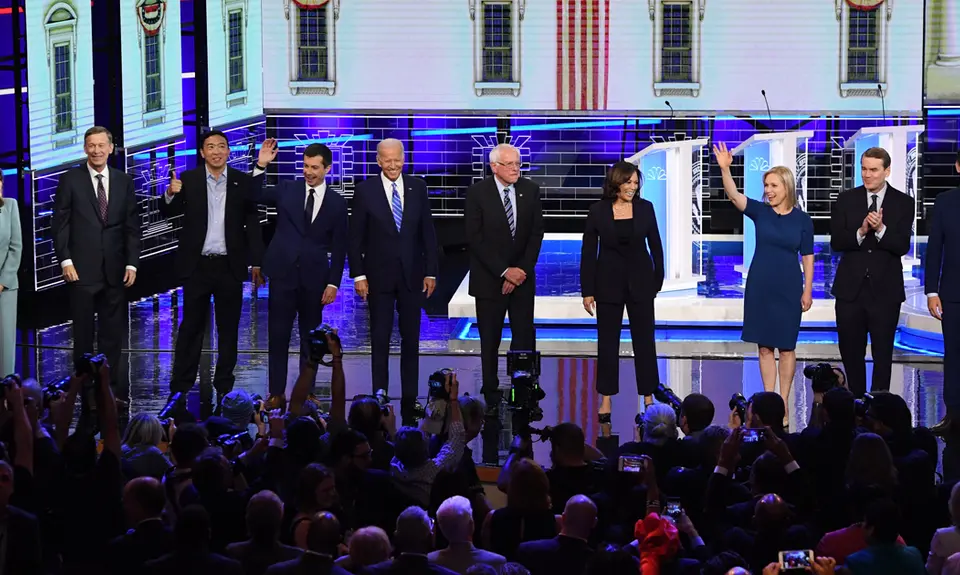 The Democratic presidential candidates smile and wave from the front of the stage at the second debate.