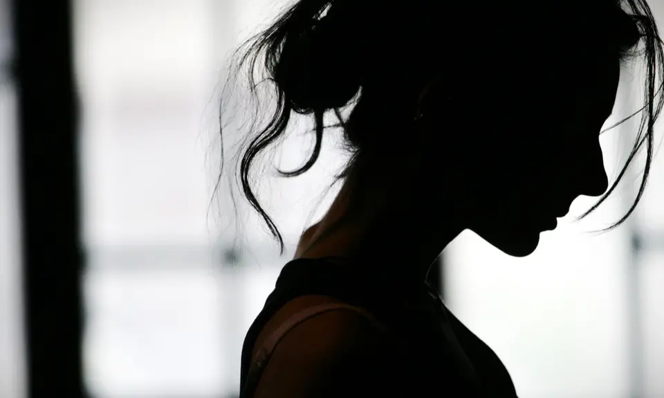 A somber black silhouette of a woman with messy hair looking down.