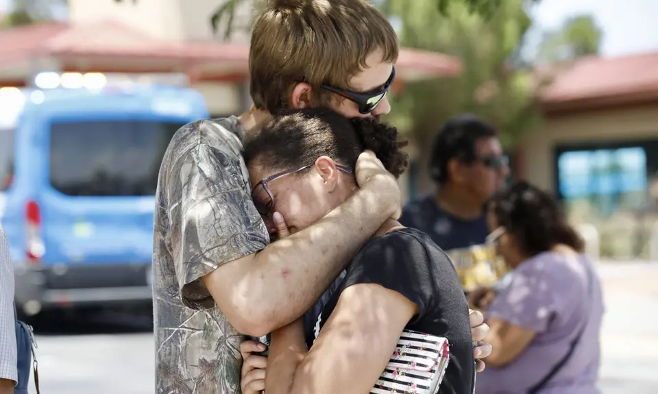 A man hugs a woman tight to his chest.