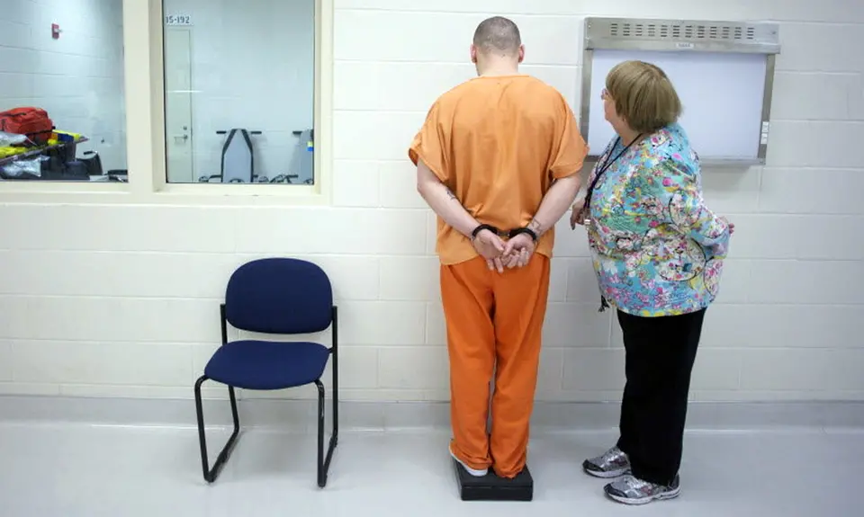 A nurse measures a prisoner's weight