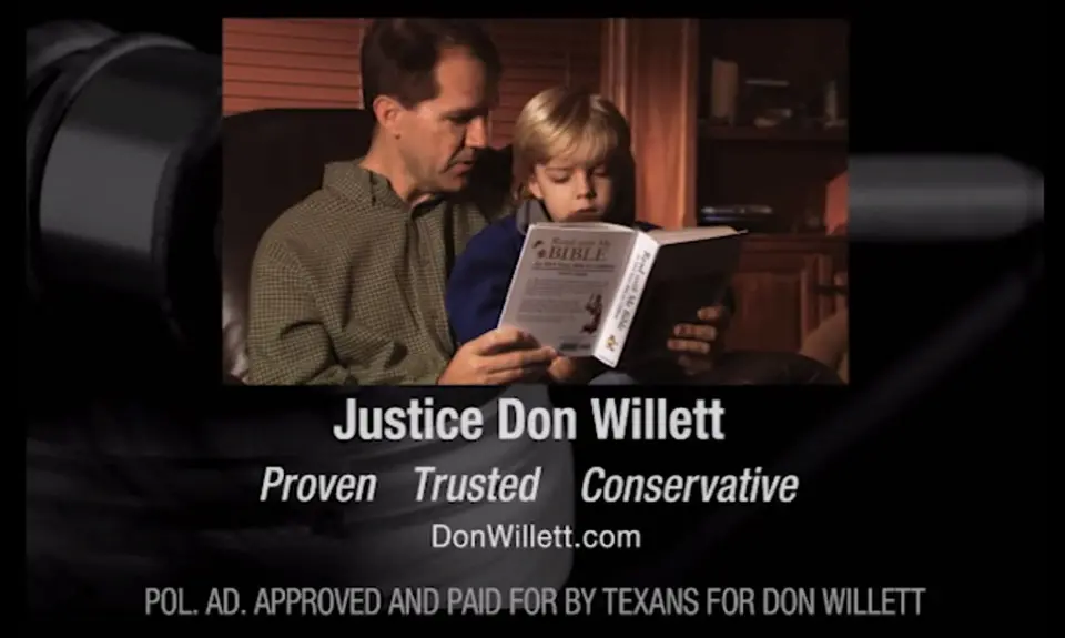 A screenshot from Don Willett's 2012 campaign ad that shows him reading the Bible with a child.