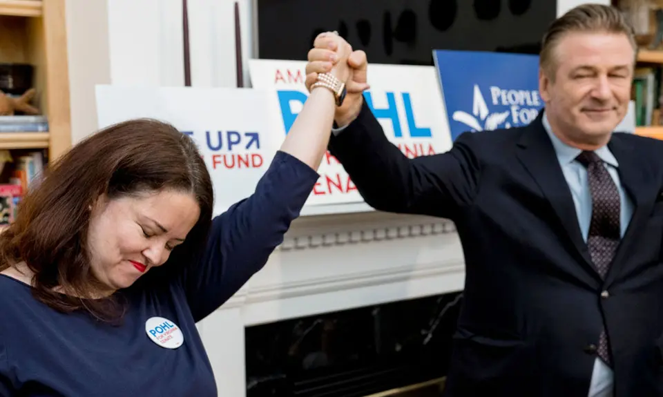 Actor Alec Baldwin holds Amanda Pohl's hand at a campaign event.