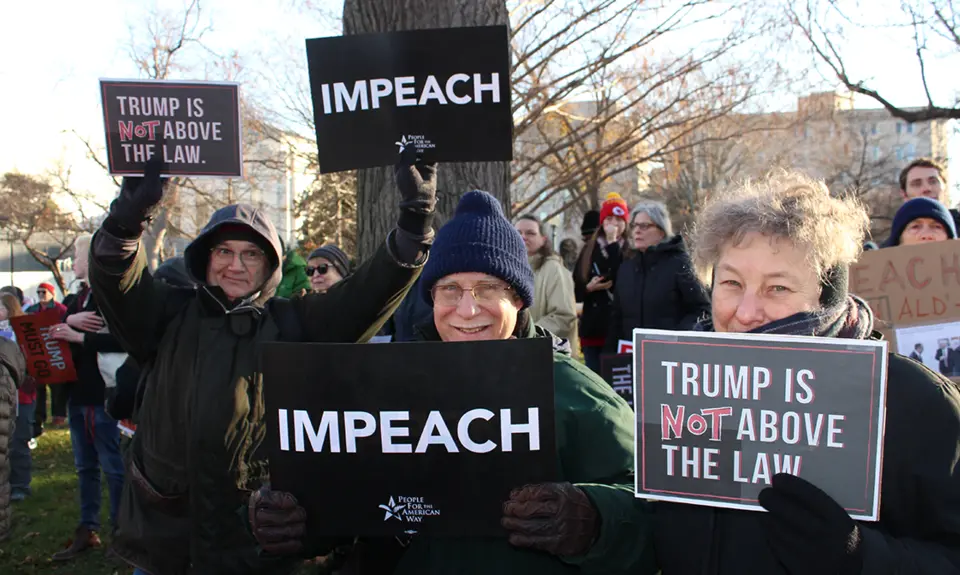 Activists hold signs calling for Donald Trump's impeachment and removal.