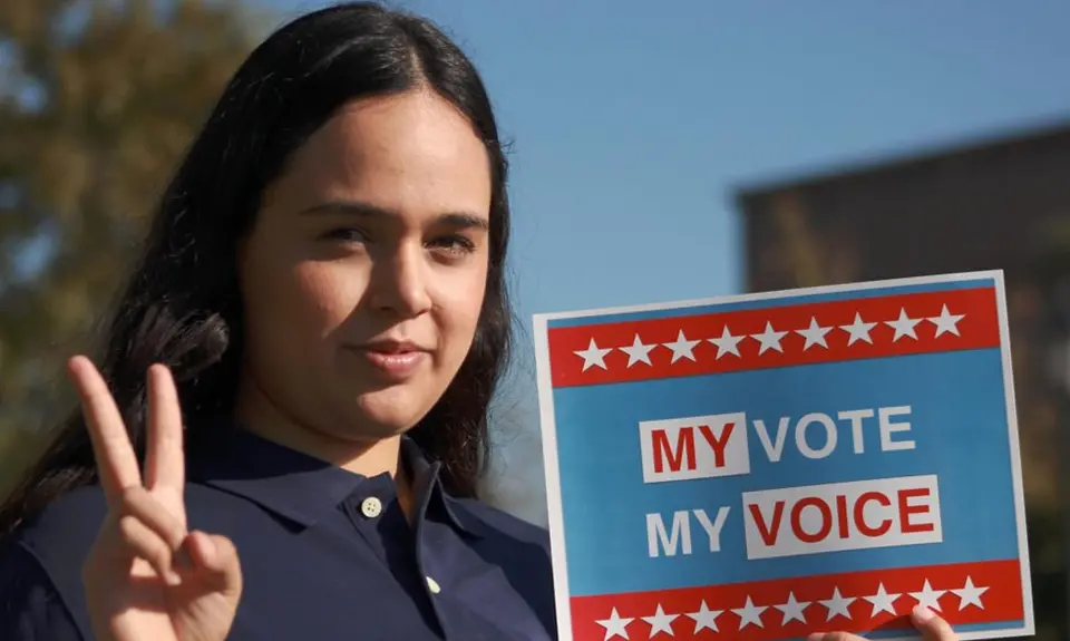 A woman holds a sign that says "My vote, my voice."