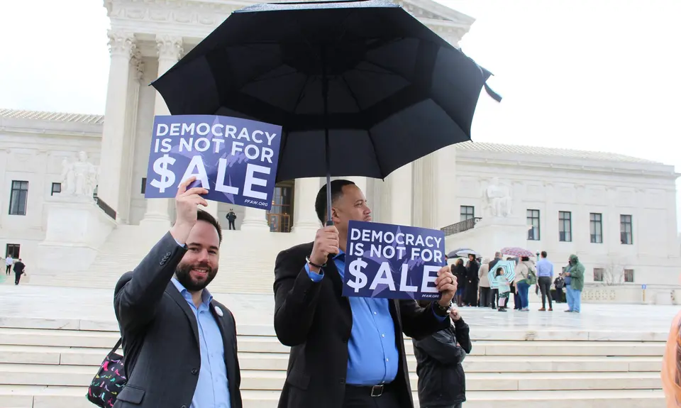 PFAW staff holds signs saying "Democracy Is Not for Sale" in front of the Supreme Court