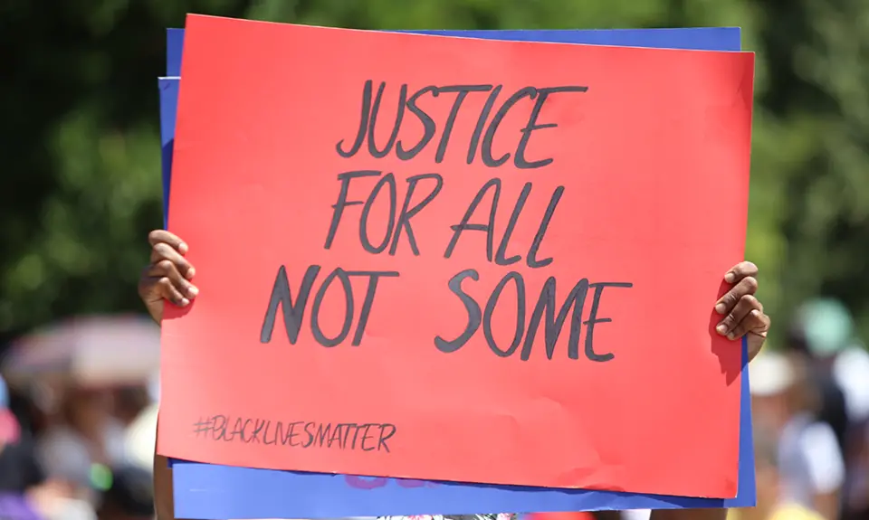 At a Black Lives Matter protest, a sign reads "Justice for All, Not Some."