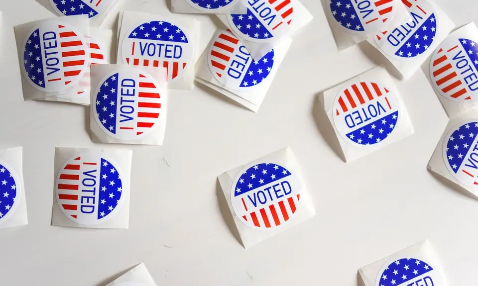 Stickers reading "I voted" are scattered on a white surface.