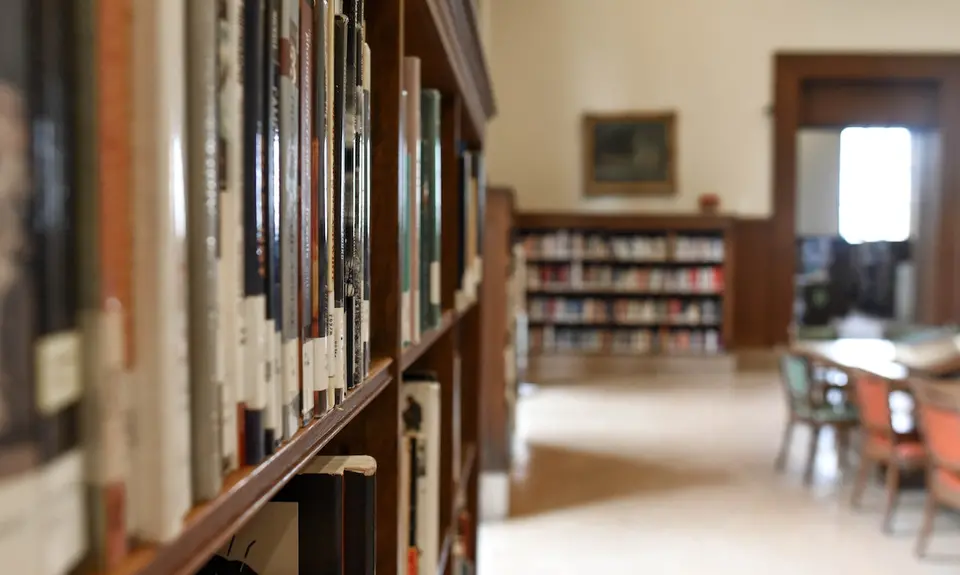 A school library bookshelf with a table in the background.