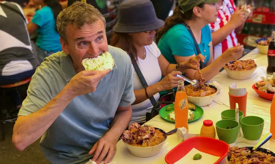 Phil Rosenthal sits at a table with several women eating food.