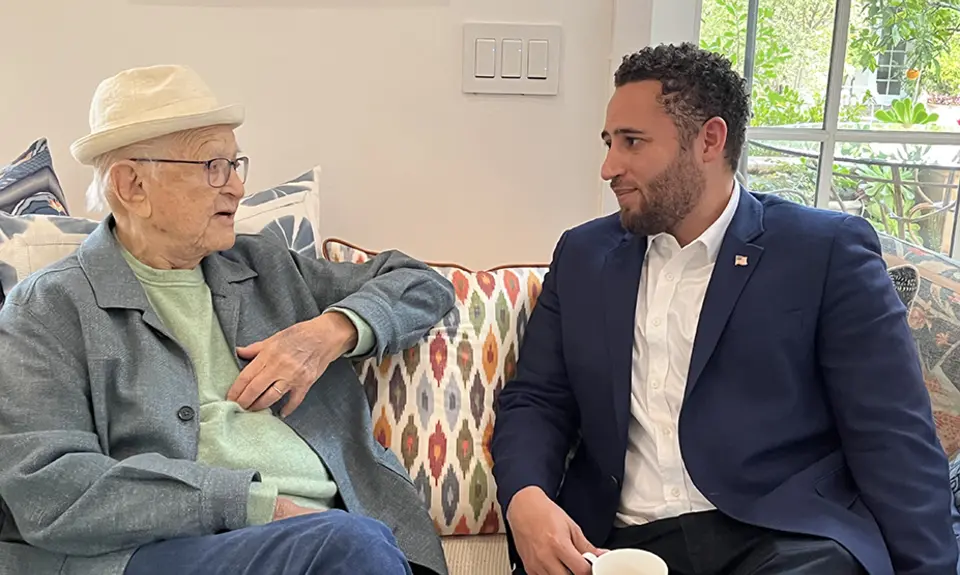 Norman Lear and Svante Myrick sit next to each other on a sofa discussing antisemitism.