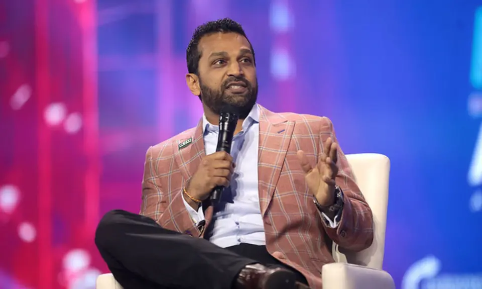 A photo of Kash Patel wearing a pink jacket and holding a microphone.