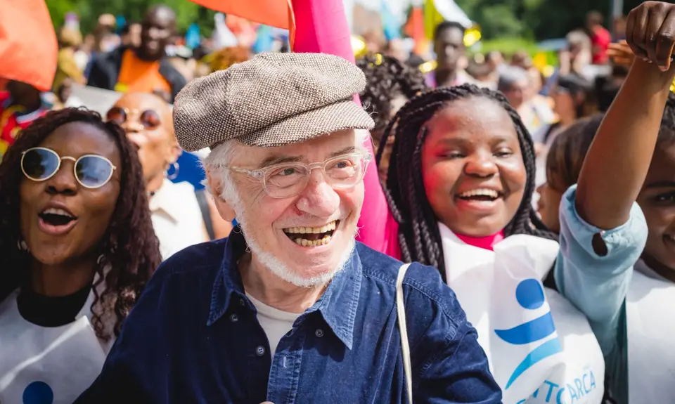 A grandparent smiling at a rally with younger people.