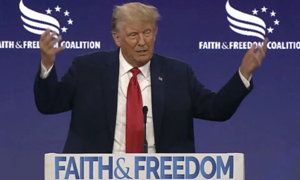 Donald Trump at a podium that reads "Faith and Freedom"