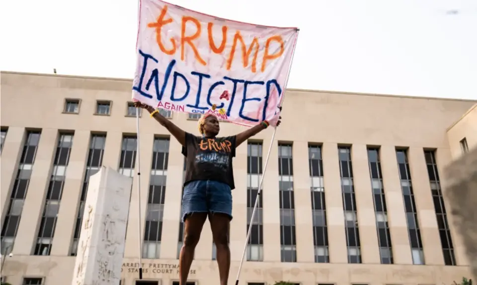 A protester displays a sign outside of the E. Barrett Prettyman U.S. District Court House in Washington, D.C., on Tuesday, Aug. 1, 2023. Members of a grand Jury met to examine former President Donald Trump’s role in the Jan. 6 riot and effort to overturn the 2020 election.