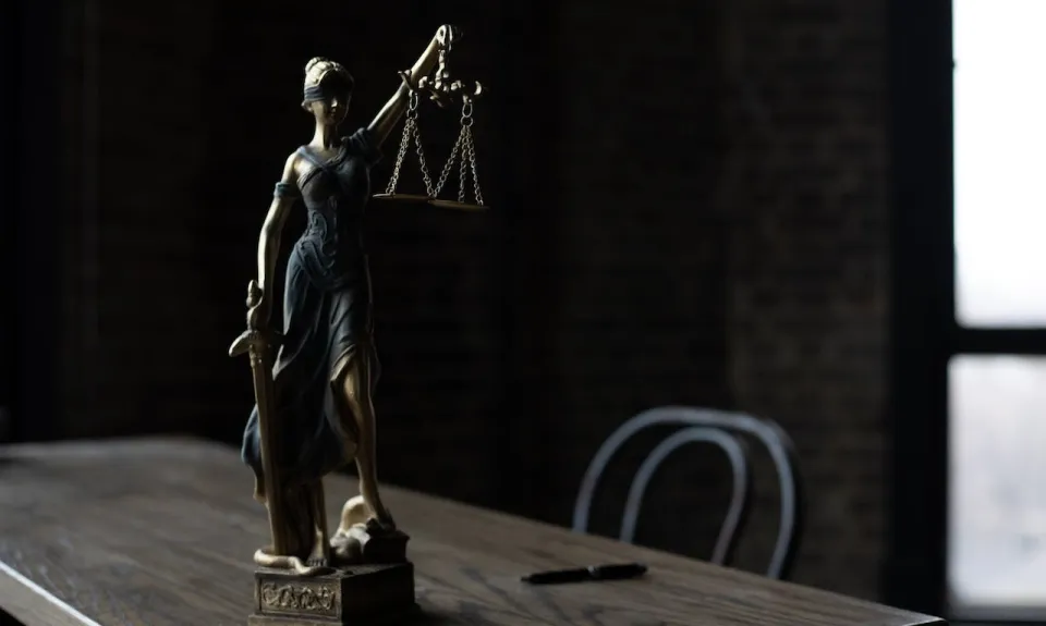 A statue of lady justice sitting on a table.