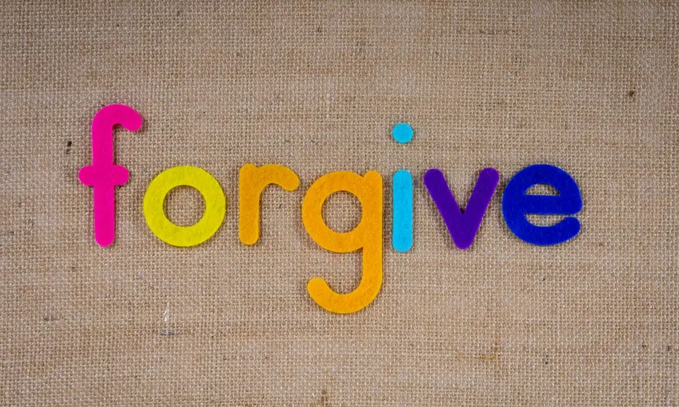 Colorful letters on a wood background. Letters spell "forgive"