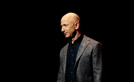 Jeff Bezos wearing a gray suit in front of a black background