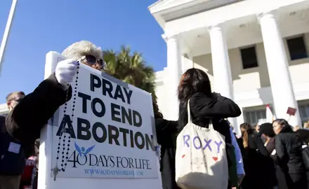 Protestors hold a sign that reads "Pray to end abortion"