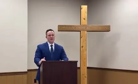 Ben Zeisloft speaking in front of a cross